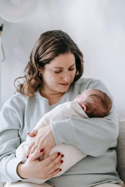 maman qui regarde son bébé nouveau né enveloppé avec amour